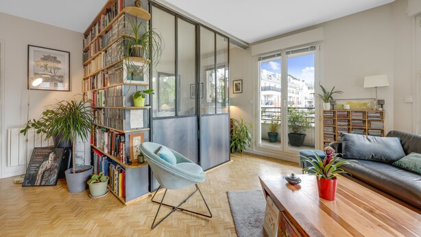 Un salon moderne avec une bibliothèque, un fauteuil bleu, un canapé et une table basse en bois.