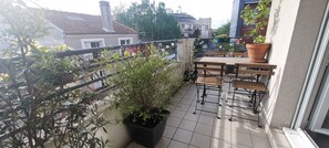 A balcony with a tiled floor, potted plants, and a wooden table with chairs. - 90 m2 chic, cosy, bright, modern, 6 mn from Paris on foot, 3 mn from the metro (Les Lilas)