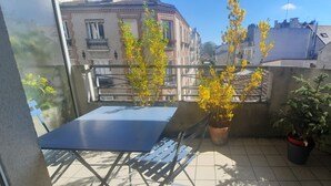 Un balcon avec une table et des chaises, des plantes en pot et une vue sur les bâtiments.