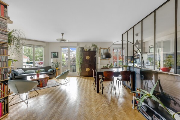 A modern living room with a sofa, coffee table, and dining area. - 90 m2 chic, cosy, bright, modern, 6 mn from Paris on foot, 3 mn from the metro (Les Lilas)