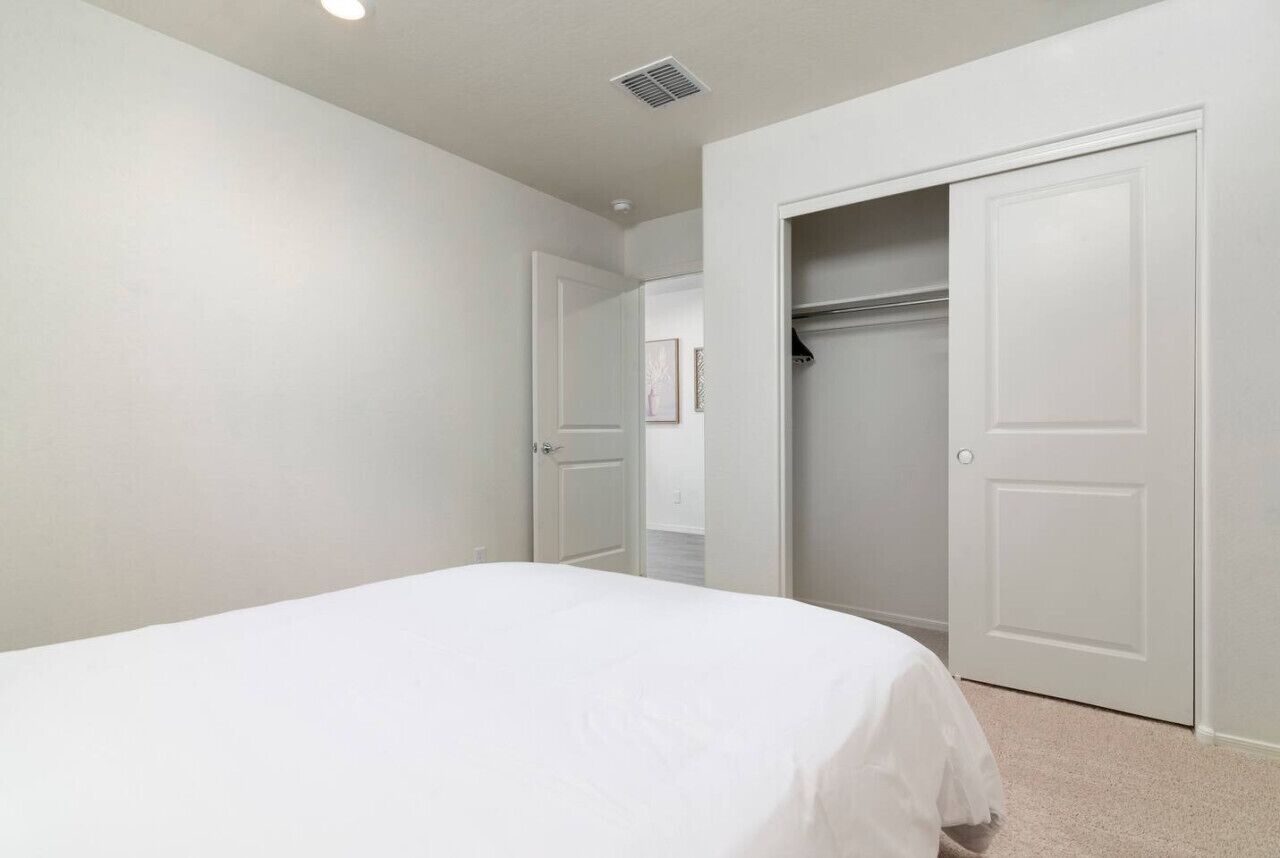 Un dormitorio con cama, armario y puerta que da a otra habitación.