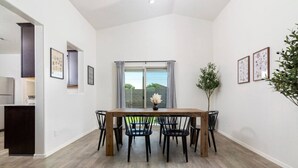 A dining area with a wooden table and black chairs, a window with curtains, and framed artwork on the walls. - *Spacious Family Oasis*Pool Table*Backyard*Garage* (Casa Grande)