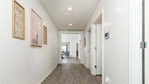 A hallway with wooden flooring, white walls, and framed artwork. - *Spacious Family Oasis*Pool Table*Backyard*Garage* (Casa Grande)
