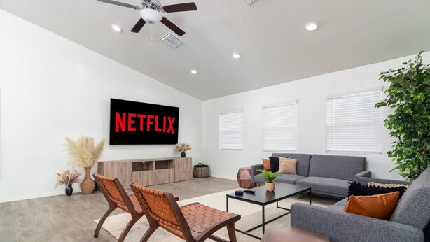 A modern living room with a grey sofa, a coffee table, and a TV displaying "NETFLIX". - *Spacious Family Oasis*Pool Table*Backyard*Garage* (Casa Grande)