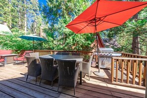 Une terrasse extérieure avec une table à manger, des chaises et un barbecue.
