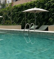 Una piscina al aire libre, sombrillas, sillones reclinables de piscina