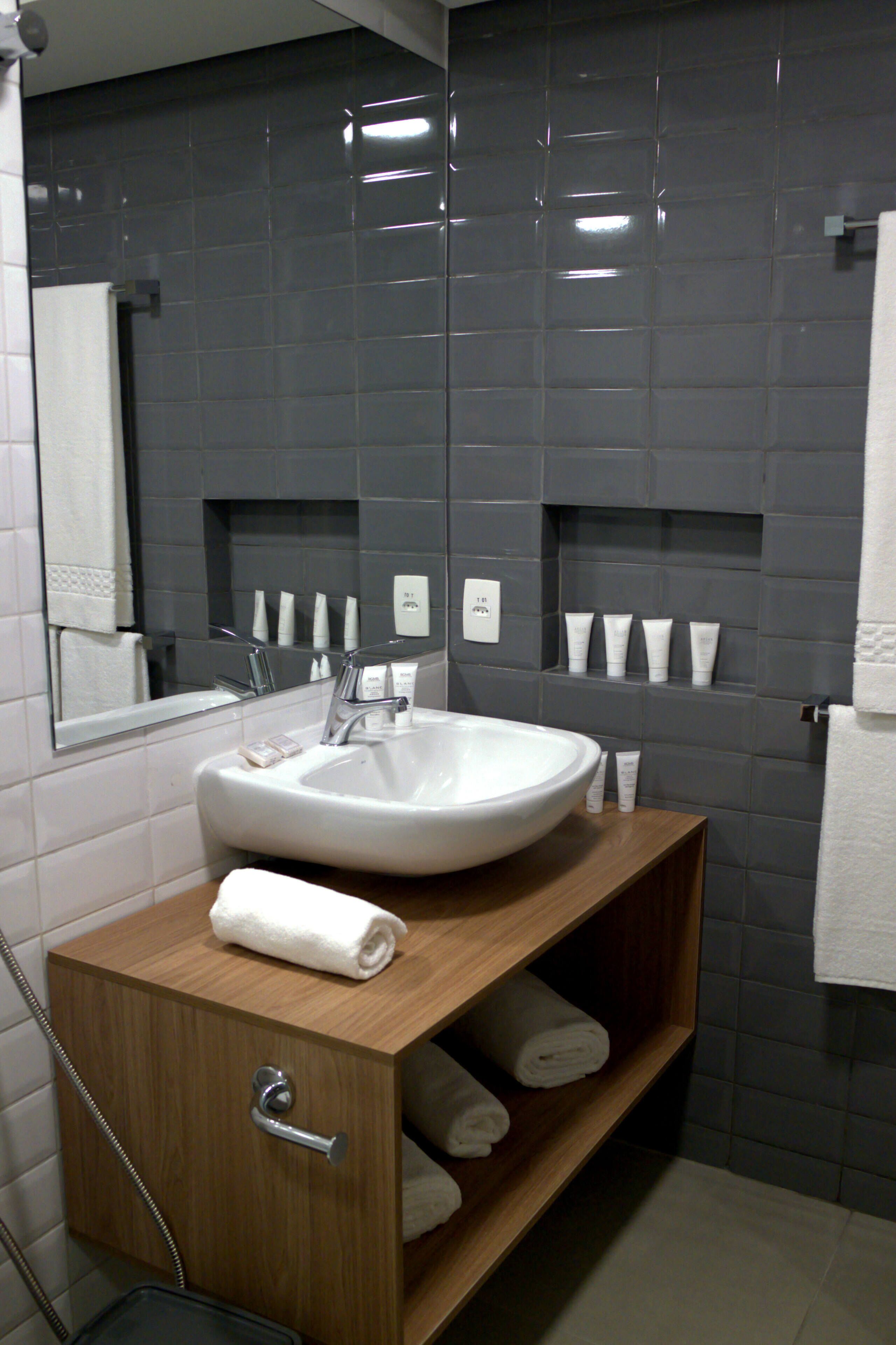 A modern bathroom with a white sink, a wooden vanity, and a mirror above it.