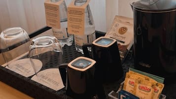 Ein Tablett mit Kaffeeautomaten, einer Wasserflasche, einem Kaffeefilterbeutel und einem Glasbehälter.