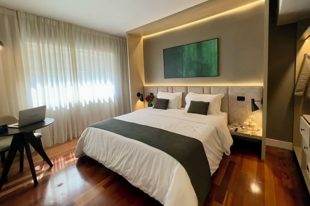 Una habitación de hotel moderna con una cama grande, un escritorio y una computadora portátil.