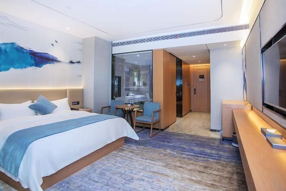 A modern hotel room with a large bed, a desk, and a TV.