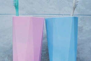 Two toothbrushes in pink and blue containers. - He Hotel (Liuyang)