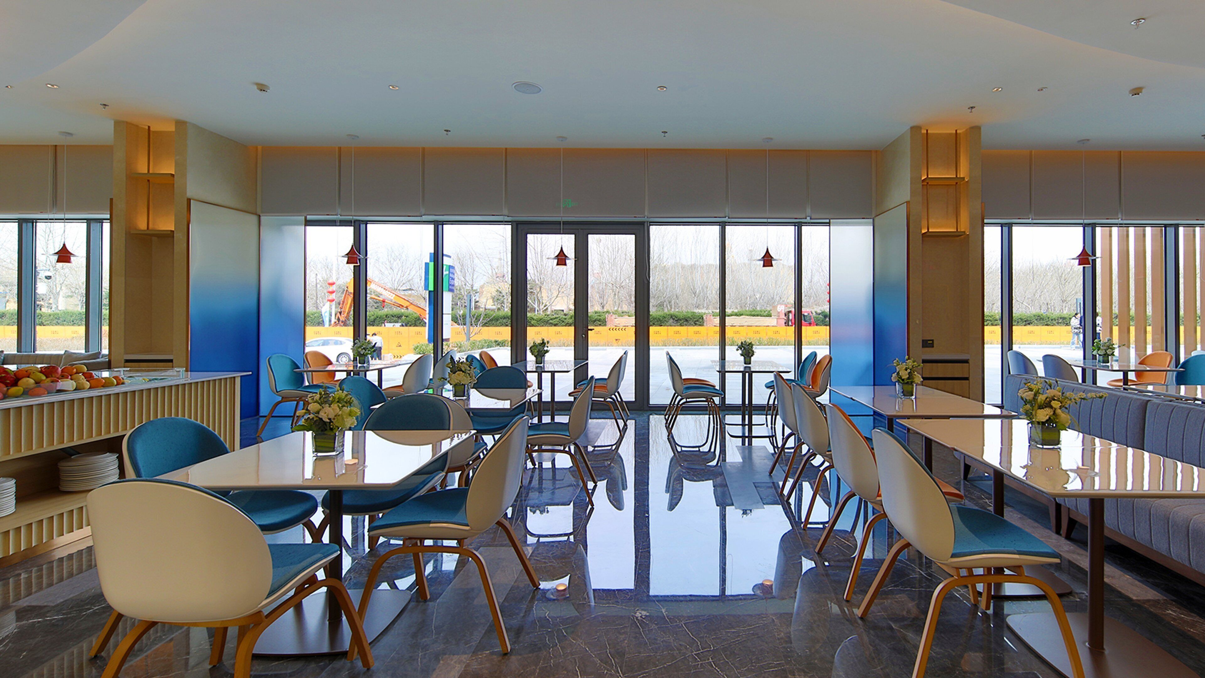 Un comedor moderno con mesas y sillas, ventanas amplias y vistas al exterior.
