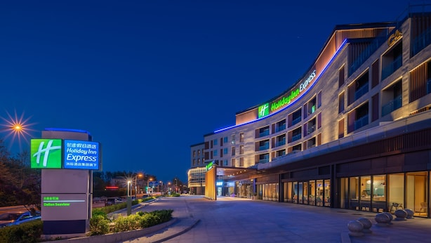 Un bâtiment de la chaîne Holiday Inn Express, doté d’un design moderne, avec une façade incurvée et une enseigne lumineuse.