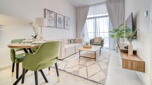 Ein modernes Wohnzimmer mit Essbereich, ausgestattet mit einer Couch, einem Couchtisch und einem an der Wand montierten Fernseher.