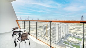 Ein Balkon mit Tisch und Stühlen, der auf eine Stadtlandschaft mit modernen Gebäuden und einem Stadion blickt.