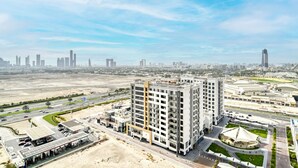 Ein hoch aufragendes Gebäude mit modernem Design, umgeben von einer gepflegten Stadtlandschaft mit Straßen und Grünflächen.