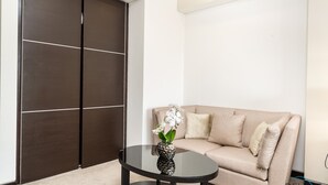 A modern room with a beige sofa, a dark wooden wardrobe, and a glass coffee table with a decorative vase.