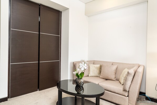 A modern room with a beige sofa, a dark wooden wardrobe, and a glass coffee table with a decorative vase.