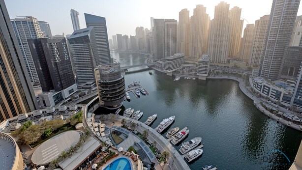 A high-rise urban area with modern architecture, a marina with boats, and a river.
