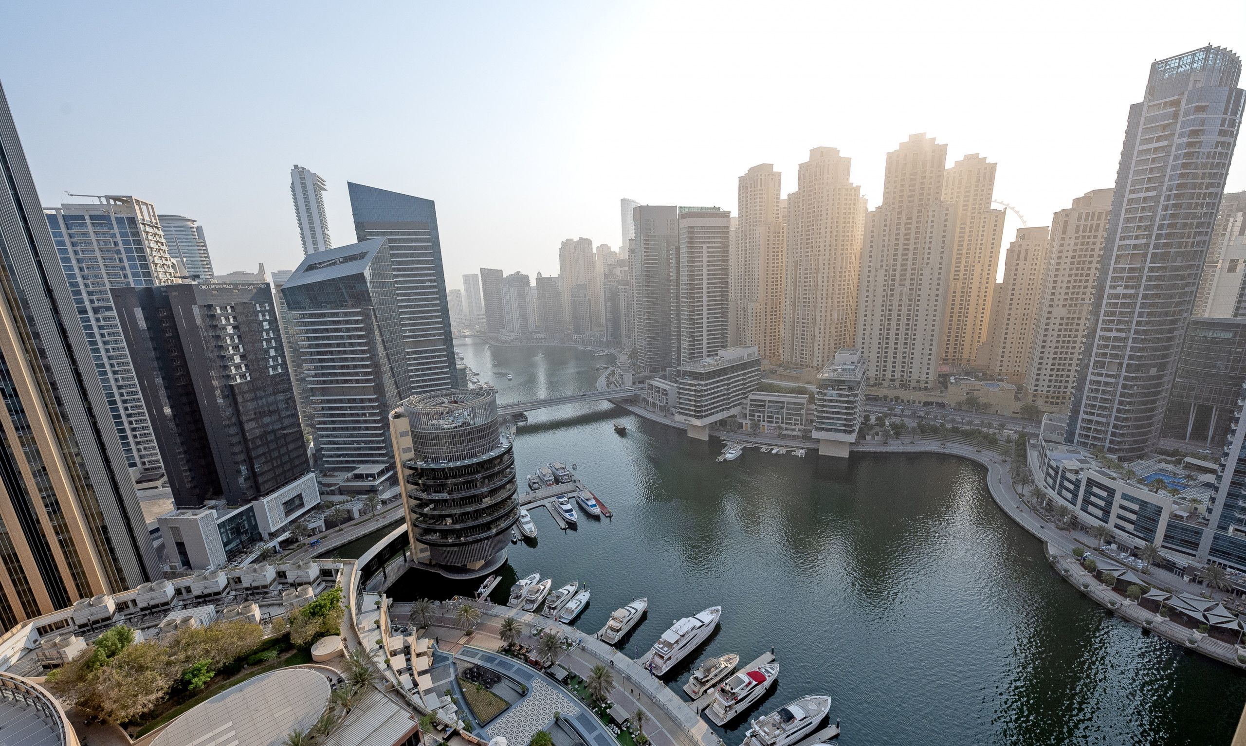 A high-rise urban area with modern architecture, a marina with boats, and a river.