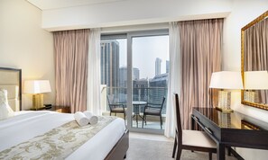 Ein Hotelzimmer mit einem großen Bett, einem Schreibtisch und einem Stuhl. Es gibt einen Balkon mit Blick auf die Stadt.