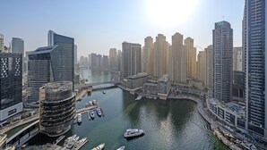 Un quartier riverain urbain avec de hauts immeubles, une architecture moderne, un port de plaisance avec des bateaux et un ciel dégagé.