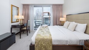 Habitación de hotel con una cama grande, dos mesitas de noche con lámparas, un escritorio con una silla y vistas a la ciudad a través de un ventanal.