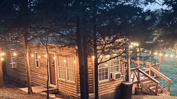A wooden cabin with a porch, windows, and a staircase leading to a deck. - Prairie Creek Cabin -Ride SxS to trails from the cabin! Kayak and Fish the Creek (Mena)