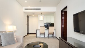 A hotel room with a sofa, a coffee table, a TV, and a kitchenette in the background. - Elegant 1BR in The Address Residences Dubai Marina by Deluxe Holiday Homes (Dubai)