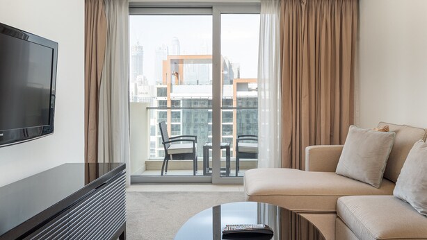 A modern living room with a flat-screen TV, a sofa, a coffee table, and a balcony with a city view. - Elegant 1BR in The Address Residences Dubai Marina by Deluxe Holiday Homes (Dubai)