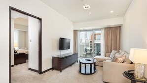 A hotel room with a large window, a flat-screen TV, a sofa, a small round table, and a cabinet. - Elegant 1BR in The Address Residences Dubai Marina by Deluxe Holiday Homes (Dubai)