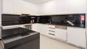 A modern kitchen with white cabinets, a black countertop, and stainless steel appliances.