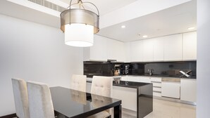 A modern kitchen with white cabinets, a black countertop, and a dining area with a glass table and chairs.