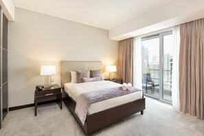 A hotel room with a large bed, two bedside lamps, a nightstand, a window with curtains, and a view of the cityscape.