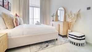 A modern bedroom with a large bed, a dresser, a mirror, and decorative plants. - Homely 1BR at Binghatti Avenue Al Jaddaf by Deluxe Holiday Homes (Dubai)