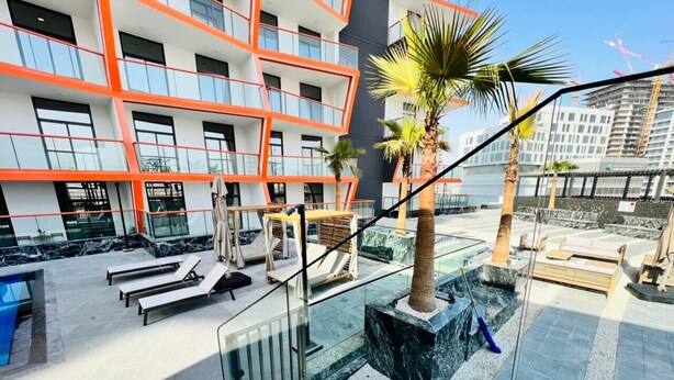 A modern hotel with a rooftop pool area, outdoor seating, and a view of the city skyline. - Homely 1BR at Binghatti Avenue Al Jaddaf by Deluxe Holiday Homes (Dubai)