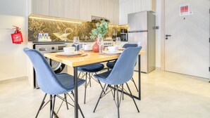 A modern kitchen with a marble backsplash, stainless steel appliances, and a dining area with blue chairs and a wooden table. - Homely 1BR at Binghatti Avenue Al Jaddaf by Deluxe Holiday Homes (Dubai)