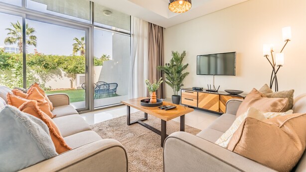 A modern living room with a sofa, coffee table, and a TV. - Flawless 3BR Townhouse with Asst's Rm at DAMAC Hills 2 Amazonia by Deluxe Holiday Homes (Dubai)