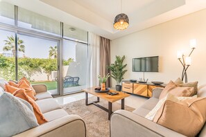 A modern living room with a sofa, coffee table, and a TV. - Flawless 3BR Townhouse with Asst's Rm at DAMAC Hills 2 Amazonia by Deluxe Holiday Homes (Dubai)