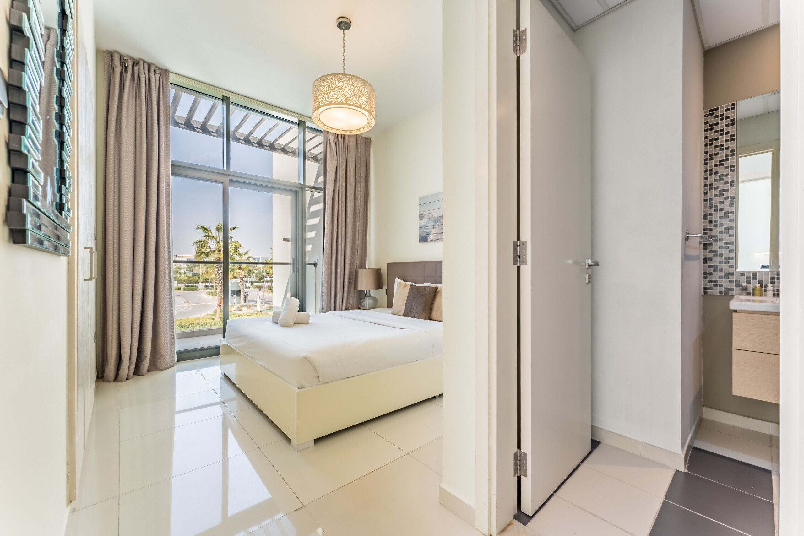 A modern bedroom with a large bed, a ceiling light, and a view of the outdoors.