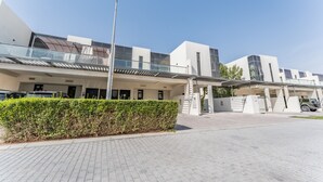 A modern building with a flat roof, large windows, and a covered walkway. - Flawless 3BR Townhouse with Asst's Rm at DAMAC Hills 2 Amazonia by Deluxe Holiday Homes (Dubai)