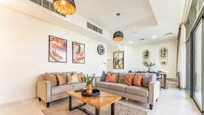 A modern living room with two sofas, a coffee table, and artwork on the walls. - Flawless 3BR Townhouse with Asst's Rm at DAMAC Hills 2 Amazonia by Deluxe Holiday Homes (Dubai)