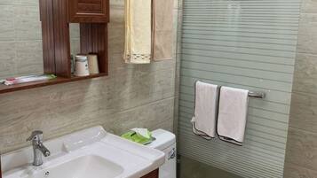 A bathroom with a sink, mirror, towel rack, and shower enclosure.