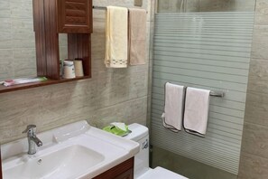 A bathroom with a sink, mirror, towel rack, and shower.