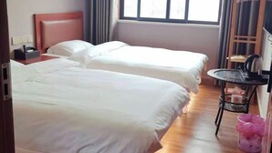 A hotel room with two beds, a small table, a chair, a window, and a coat rack. - A Rest in Xinchang (Xinchang)