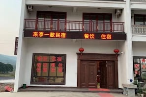 A two-story building with a balcony and a signboard indicating it is a guesthouse. - A Rest in Xinchang (Xinchang)