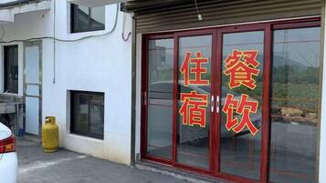 A hotel with a red-framed entrance door and a sign with Chinese characters.