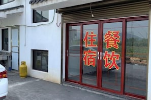 A hotel with a red-framed entrance door and a sign with Chinese characters. - A Rest in Xinchang (Xinchang)