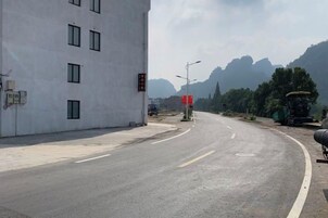 Una carretera que se curva a la derecha, con un edificio a la izquierda y montañas al fondo.