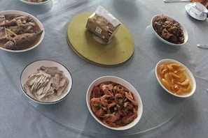 A round table with various dishes, including seafood and a package in the center. - A Rest in Xinchang (Xinchang)
